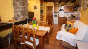 a kitchen and a living room with a table and a couch at El Bulín de Braojos - 3 Casas in Braojos de la Sierra