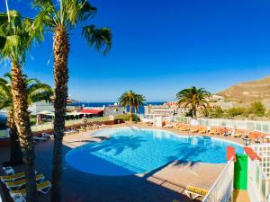 a view of a swimming pool with palm trees and the ocean at Casa Solaris at Anfi Beach with Private Terrace, Pool & Netflix in Arguineguín