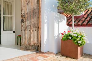 uma porta de madeira com um vaso de flores ao lado de uma casa em São Paulo Boutique Hotel - SPBH em Tavira