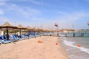 a beach with chairs and umbrellas and the ocean at Seaview Chalets in Porto South Beach - Families Only in Ain Sokhna