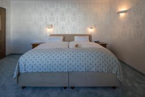 a bedroom with a large white bed with a teddy bear on it at Hotel Albona Nova in Zürs am Arlberg