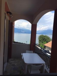 balcón con mesa, sillas y vistas al agua en Albergo Riva, en Reno Di Leggiuno