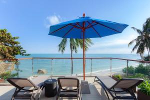 un patio con mesa, sillas y sombrilla azul en Royal Beach Boutique Resort & Spa Koh Samui - SHA Extra Plus, en Lamai