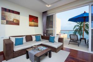 Royal Beach Boutique Resort & Spa Koh Samui - SHA Extra Plus في شاطئ لاماي: غرفة معيشة مع أريكة ومظلة
