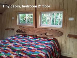 ein Schlafzimmer mit einem Bett und zwei Fenstern in der Unterkunft karukinka in Chonchi