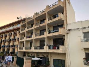 an apartment building with people walking in front of it at Mellieha Seaside Apartment in Mellieħa