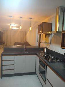 a kitchen with white cabinets and a stove top oven at Apartamento super confortável, Torres RS in Torres