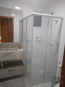 a white bathroom with a shower and a sink at Apartamento super confortável, Torres RS in Torres