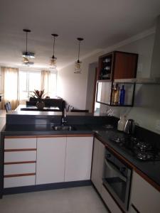 a kitchen with white cabinets and a black counter top at Apartamento super confortável, Torres RS in Torres
