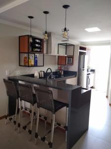 a kitchen with a black counter and some chairs at Apartamento super confortável, Torres RS in Torres