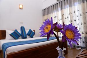 a bedroom with a bed with purple flowers in a vase at Kings Villa Galle in Galle