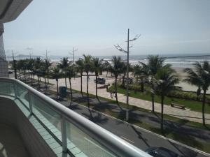 Elle offre une vue sur une rue bordée de palmiers et la plage. dans l'établissement Apartamento Praia Grande Pé na areia, à Solemar