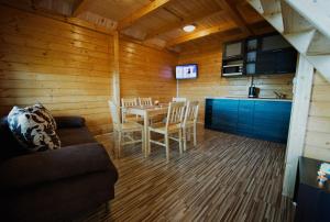 a living room with a table and chairs and a kitchen at Ross-domki in Sarbinowo