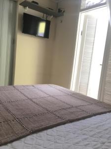 a bedroom with a bed and a flat screen tv at SUÍTES Caminho do Mar in Abraão