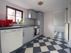 a kitchen with white cabinets and a checkered floor at Ferienhaus von Alvensleben in Hameln +7 photos