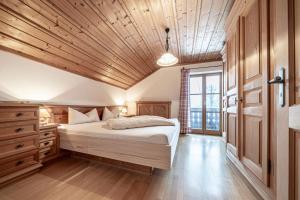 - une chambre avec un lit et un plafond en bois dans l'établissement Lamprechthof, à Lenggries