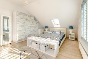 a white bedroom with a bed and a wooden floor at Villa Pastelowa in Jastarnia