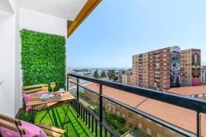 a balcony with a table and chairs and a green wall at iloftmalaga Calle Alemania I in Málaga