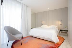 a bedroom with a white bed and a white chair at Sea Side Luxury Apartment in Figueira da Foz