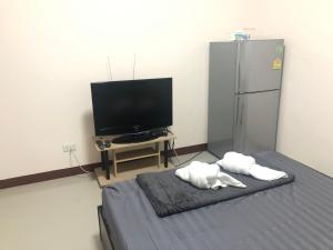 a room with a television and a bed with two towels at TP home in Bangkok