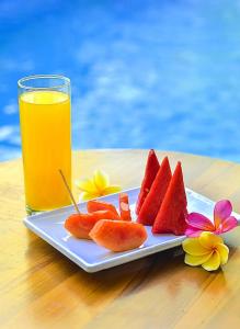 a plate of fruit on a table with a glass of orange juice at The Puncak Santhi Inn in Nusa Penida