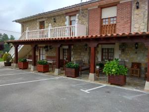 a building with a balcony and plants in a parking lot at Hospedaje Vega in Santillana del Mar
