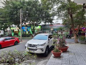 une voiture blanche garée sur le côté d'une rue dans l'établissement Hotel Phú Sĩ, à Hô-Chi-Minh-Ville