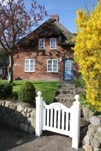 a white fence in front of a brick house at Reetdachhaus Ohl Dörp in Wyk auf Föhr