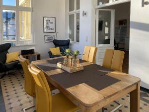ein Esszimmer mit einem Holztisch und gelben Stühlen in der Unterkunft Villa Anna - Carpe Diem in Heringsdorf
