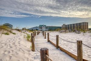a wooden walkway to the beach with buildings in the background at Plantation West Resort in Gulf Shores