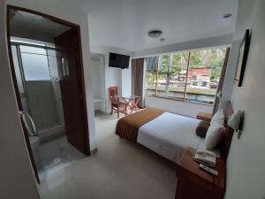 1 dormitorio con cama, ducha y ventana en Flower's House, en Machu Picchu