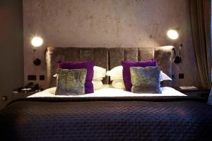 a bedroom with a large bed with purple pillows at Malmaison London in London