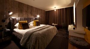a hotel room with a bed with yellow pillows at Malmaison London in London