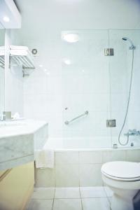 a white toilet sitting next to a bath tub in a bathroom at MR Hotel Providencia (ex Hotel Neruda) in Santiago