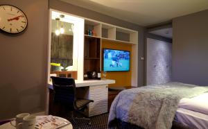 a bedroom with a bed and a desk and a tv at Malmaison London in London