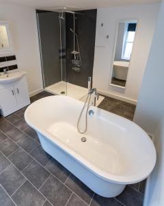 a white bath tub in a bathroom with a shower at Ocean Apartment, 50 yds to Beach, Sleeps 10 in Weymouth
