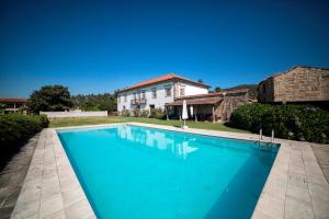 a large blue swimming pool in front of a house at Casa de Sta Comba in Barcelos