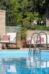 a swimming pool with two chairs and a table and a pool at Heritage Hotel Tisno in Tisno