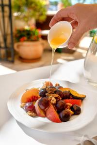 ティスノにあるHeritage Hotel Tisnoの果物の皿に蜂蜜を注いでいる人