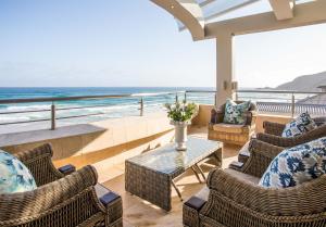a balcony with chairs and a table and the ocean at Waves of Grace Seafront Villa in Herolds Bay