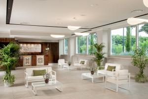 a lobby with white chairs and tables and windows at Hotel Cristoforo Colombo in Rome