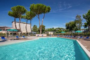 una piscina con sedie e ombrelloni in un hotel di Hotel Cristoforo Colombo a Roma
