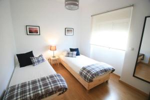 a bedroom with two beds and a window at D. João I Apartment in Almada