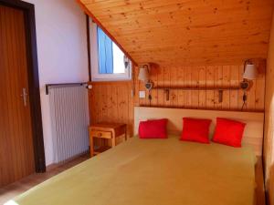 um quarto com uma cama com duas almofadas vermelhas em Romantic Chalet-Style Flat with Mountain View em Torgon