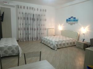 a bedroom with two beds and a table and chairs at Mediterranea Guest House in Porto Cesareo