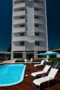 un hôtel avec une piscine, des chaises et un bâtiment dans l'établissement Favorita Golden Hotel e Eventos, à São José