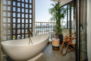 a bath tub in a bathroom with a balcony at Seahorse Tropical Da Nang Hotel by Haviland in Da Nang