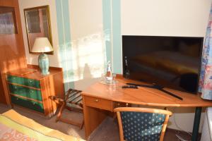 Habitación con escritorio, TV y silla. en Marschalls Hotel Am Rennsteig en Neuhaus am Rennweg