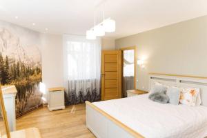 a white bedroom with a large bed and a window at Brand-New Deluxe Apartment in Liepāja in Liepāja