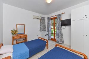 a bedroom with two beds and a tv and a mirror at Eretria Park Studios in Eretria